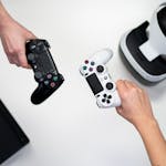 Black and white gaming controllers with VR headset on a minimalist background.
